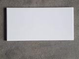 an overhead view of a white rectangular tile on a concrete floor
