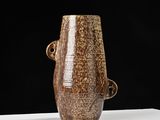 un vase marron posé sur une table blanche