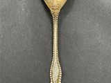 a gold spoon with a long handle sitting on top of a table