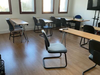 des tables et des chaises dans une salle de classe, avec un téléviseur à écran plat accroché au mur
