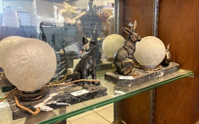une étagère en verre sur laquelle sont posées quelques statues, dans une pièce