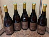 six bottles of wine are lined up on a wooden table