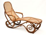 une photo d'une chaise longue en osier avec un repose-pieds