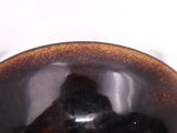 a brown bowl with a black lid on a white table