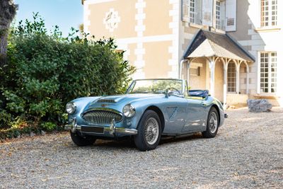 une voiture bleue garée devant une grande maison