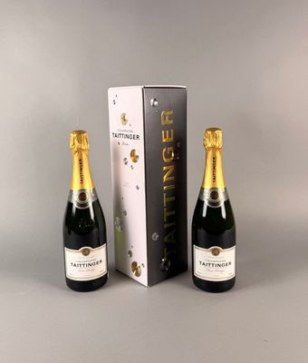 deux bouteilles de champagne posées à côté d'un carton de vin sur une table