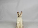 porcelain figurine of a white dog sitting on a wooden block