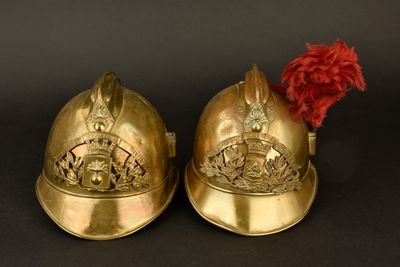 une paire de casques en laiton surmontés d'une plume rouge