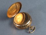 a gold pocket watch sitting on a blue surface