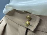 beige pleated skirt with gold buttons on a mannequin mannequin mannequin mannequin mannequin mannequin mannequin manne