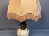 a white lamp with a beige shade on it