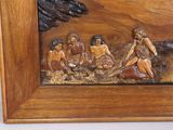 carvings of a group of people in a wood frame on a wall