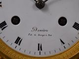 a gold clock with roman numerals on the face