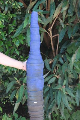 a person holding a blue vase in front of a bush