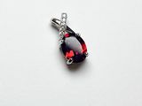 une image représentant un pendentif orné d'une pierre rouge sur fond blanc