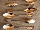 six silver spoons are lined up on a table with a price tag