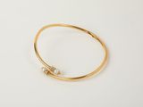 a gold bang bracelet with a single pearl bead on it