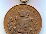 une vieille médaille ornée d'une couronne, posée sur un fond blanc