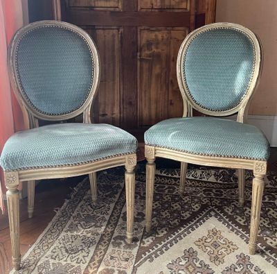 une paire de fauteuils rembourrés bleus posés sur un tapis devant un meuble en bois