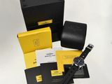 the watch is sitting next to a black box and a yellow box