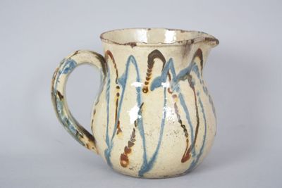 a white pitcher with blue and brown designs on it