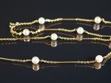chaîne en or ornée de perles, posée sur un fond noir