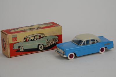 une petite voiture et une boîte posées sur une surface blanche, avec une autre boîte en arrière-plan