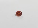 an orange sapphire stone on a white surface