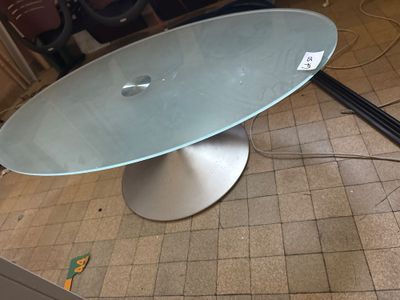 une table en verre avec un piètement en métal, posée sur un sol carrelé