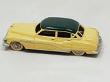 a yellow toy car with a green roof on a white surface