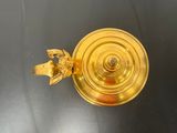 gold plated candle holder on black table with a gold plated candle holder
