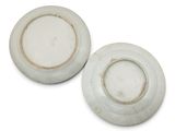 pair of white porcelain plates on a white surface with a brown rim