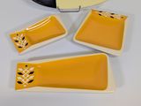 yellow and white ceramic dishes with black and white designs and a vinyl record on a table