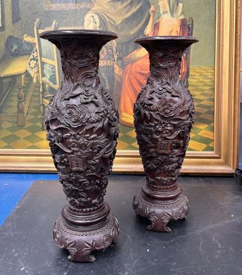 deux vases posés sur une table devant un tableau