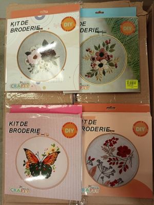 quatre kits de broderie au point de croix dans une boîte ornée d'un papillon