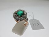 gros plan d'une bague avec une pierre verte entourée de diamants