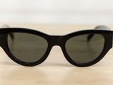 une paire de lunettes de soleil noires posée sur une table en bois