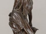 bronze statue of a woman holding a pot on a wooden table