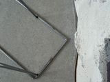 a broken piece of metal on the ground next to a wall