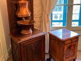 a small table with a lamp on it next to a cabinet with a lamp on top of it