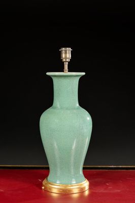 a green vase on a red table with a gold base