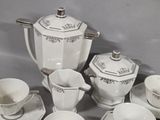 a white tea set on a table with silver trimmings