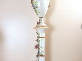 a white vase with flowers on it sitting on a table