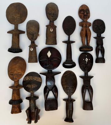 Plusieurs figurines africaines en bois sont disposées sur une surface blanche