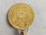 a gold coin on a metal pin on a white surface