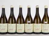 six bouteilles de vin sont alignées sur une surface blanche