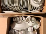 de nombreuses assiettes et tasses dans une boîte posée par terre