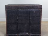 an old black trunk sitting on top of a floor next to a white wall