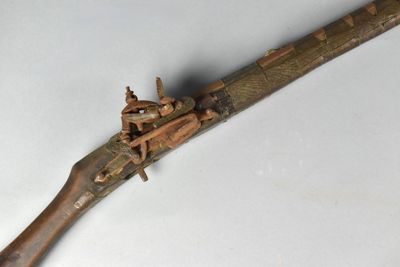 un vieux pistolet avec une poignée en bois sur une surface blanche