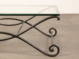an iron and glass coffee table with a glass top